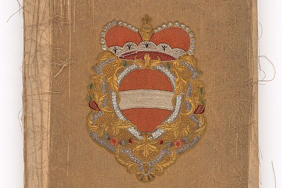Foto von Buchdeckel mit österreichischem Wappen mit Krone, der Einband löst sich in Fasern auf
