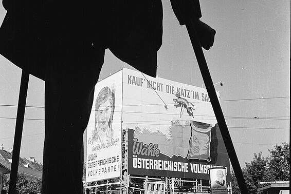 Ein Kriegsversehrter betrachtet ein Wahlplakat. Schwarzweiß-Fotografie