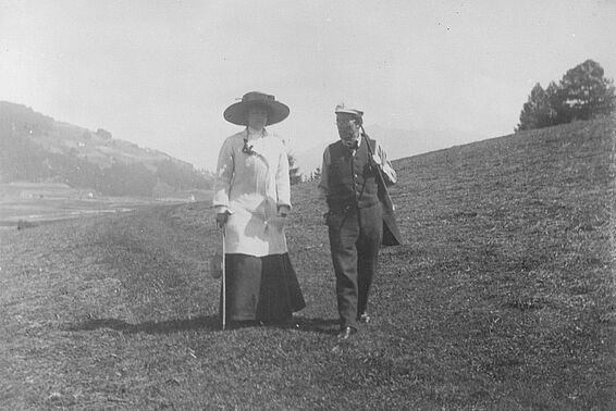 Eine Frau und ein Mann in altmodischer Kleidung bei einem Spaziergang auf einem Hügel, schwarz-weiß