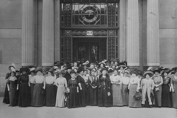 Gruppenfoto von in etwa sechzig Frauen vor einem prunkvollen Gebäude, alle tragen lange Röcke und Hüte, schwarz-weiß