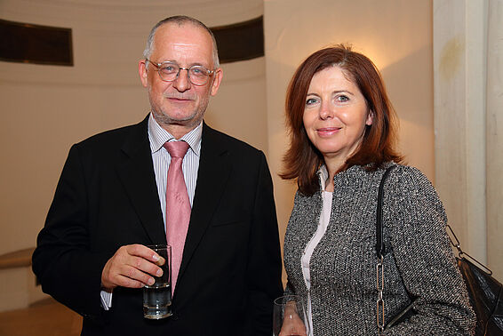 Ein Mann und eine Frau in eleganter Kleidung posieren mit Getränken