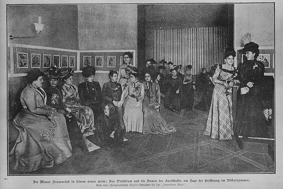 Etwa zwanzig Frauen in altmodischer Kleidung sitzen oder stehen in einem Raum, schwarz-weiß